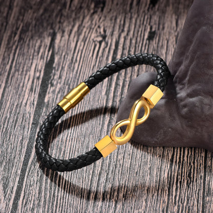 Black braided bracelet with gold infinity symbol on a wooden surface