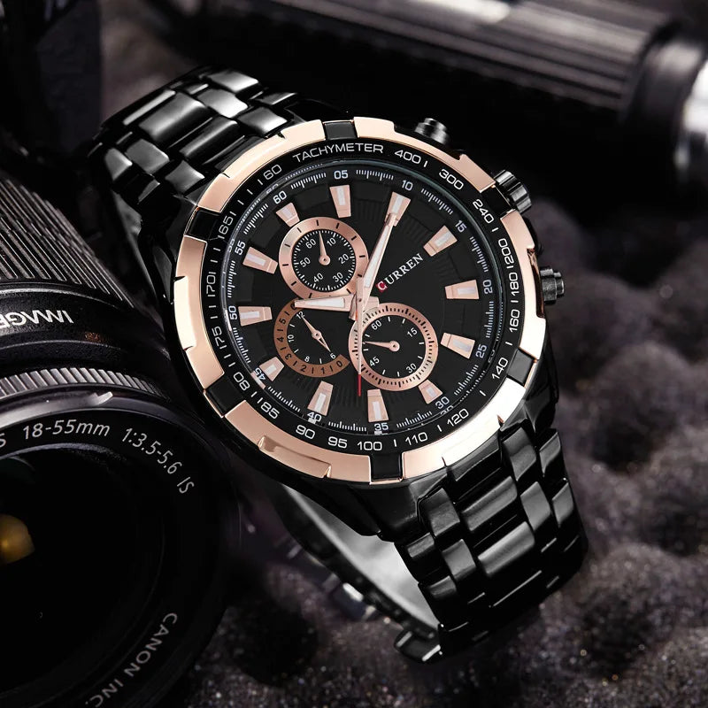 Luxury watch with black and rose gold design on a textured surface with camera lens in background