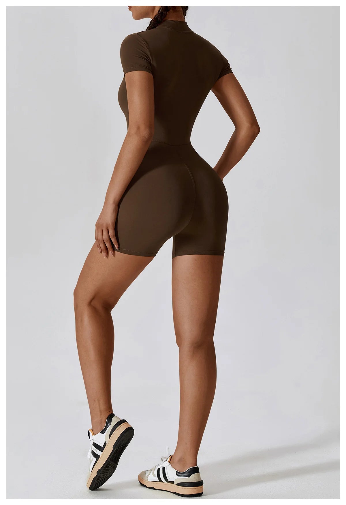 Person wearing a brown bodysuit on a light gray background