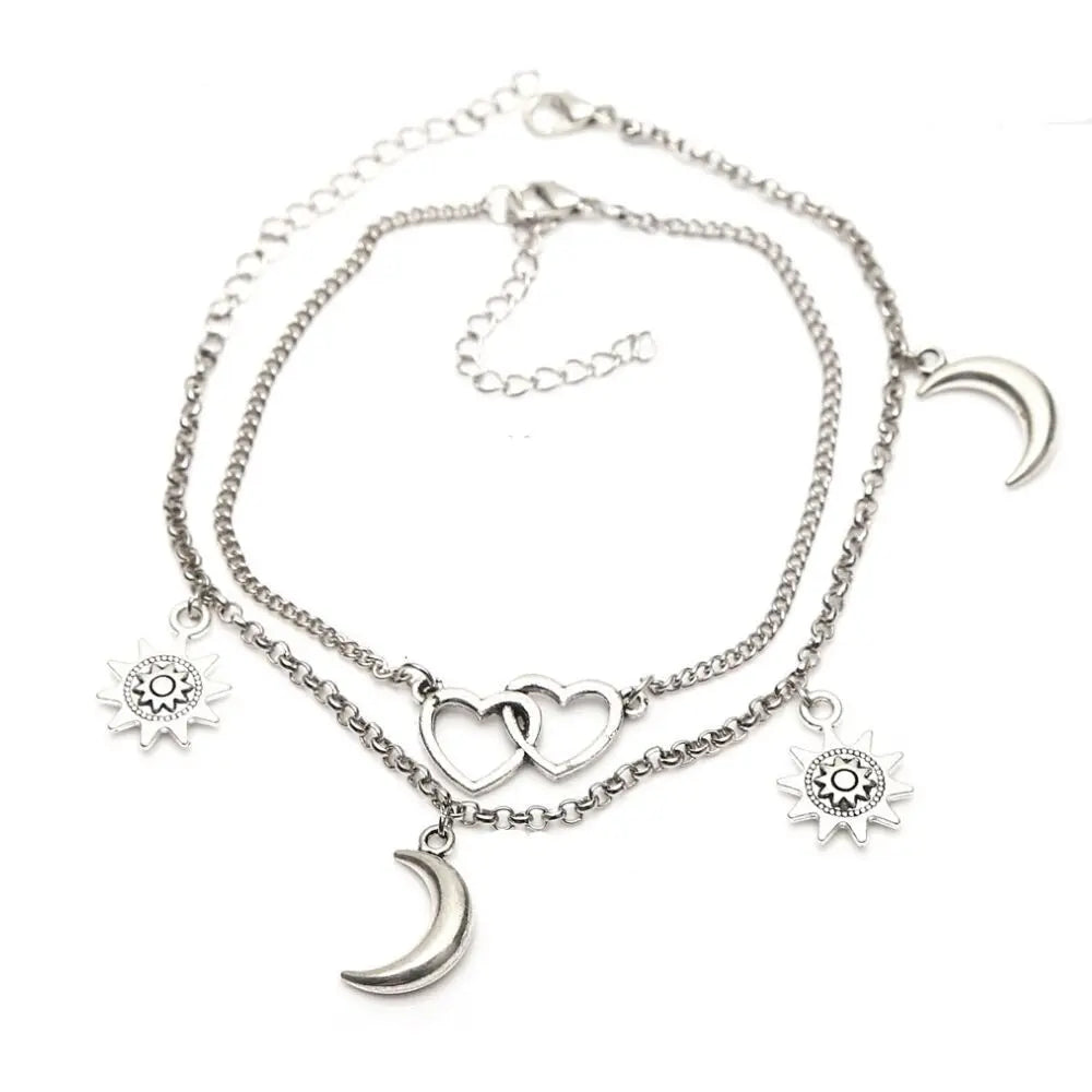 Silver anklet with heart, moon, and sun charms on a white background