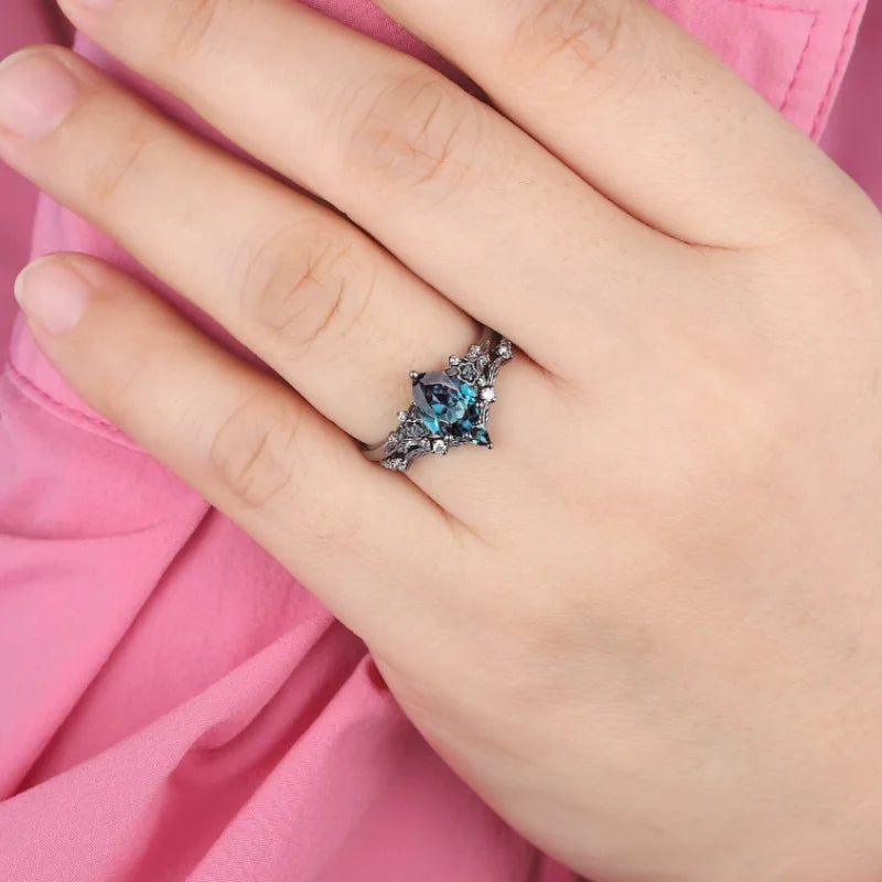 Close-up of a hand wearing a ring with a blue gemstone against a pink background
