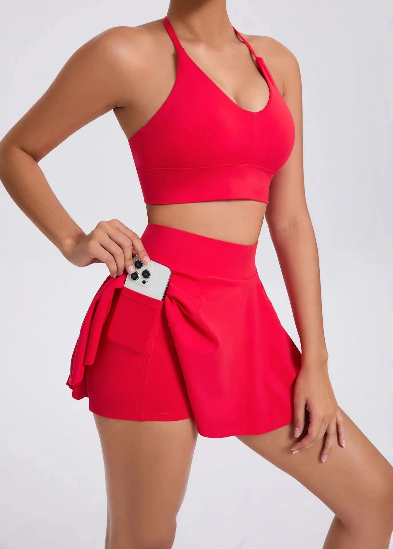 Person wearing a red sports bra and skirt set on a white background