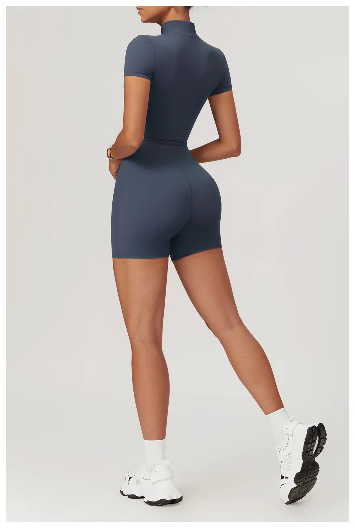Person wearing a navy blue bodysuit on a light gray background