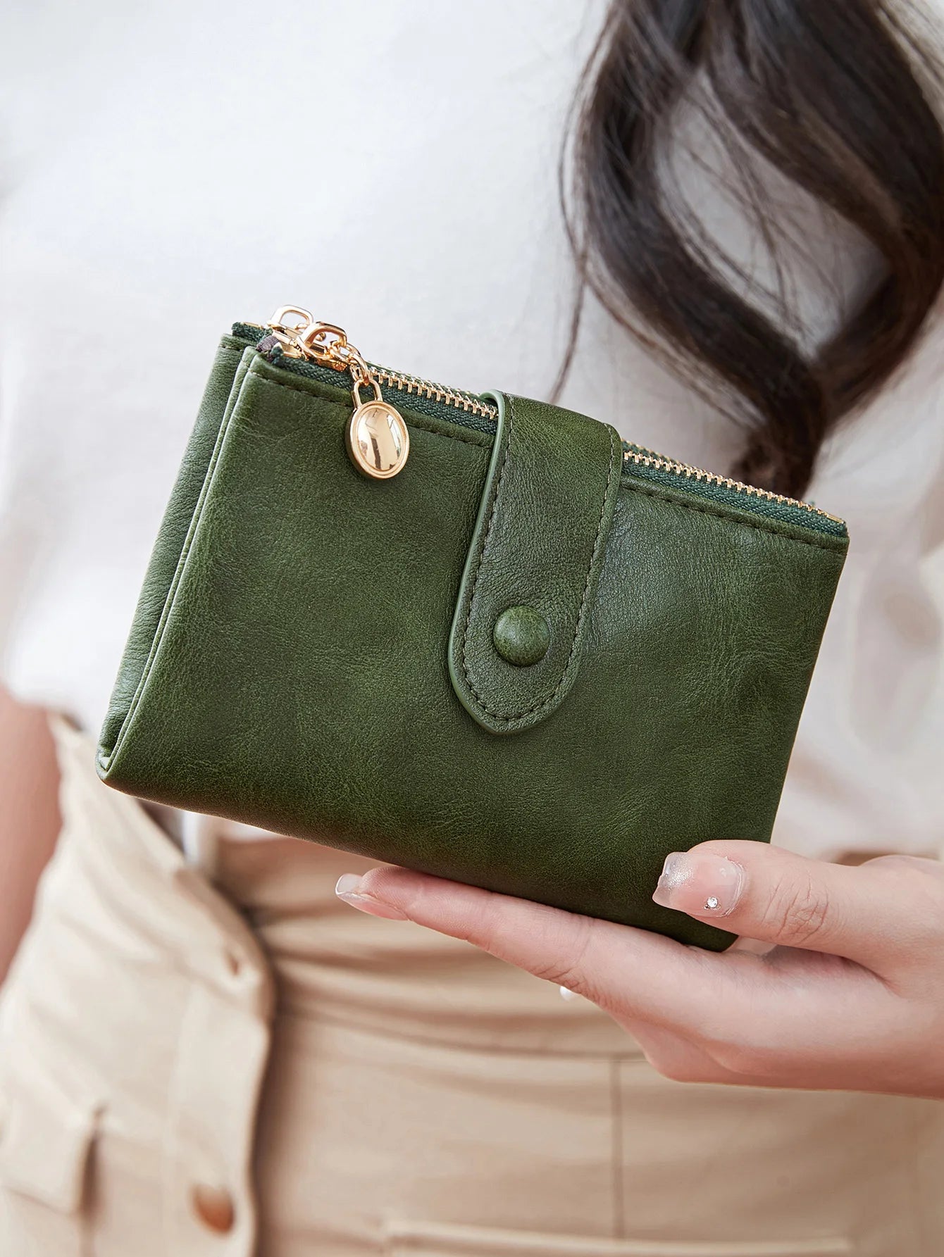 Green wallet held by a person with a blurred background