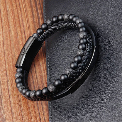 Black beaded bracelet with braided design on a wooden and leather background