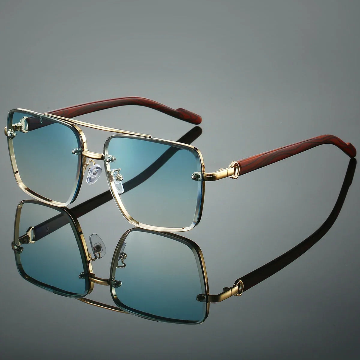 Sunglasses with gold frame and brown arms on a reflective surface with a gray background