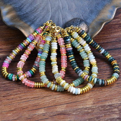 Set of colorful beaded bracelets with gold accents on a wooden surface