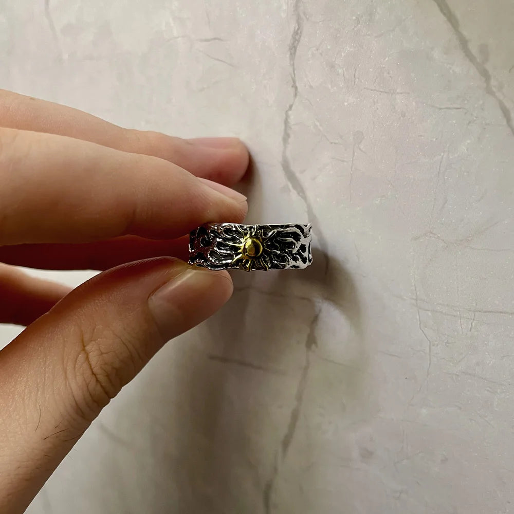 Silver ring with a spider design held by a hand against a light background