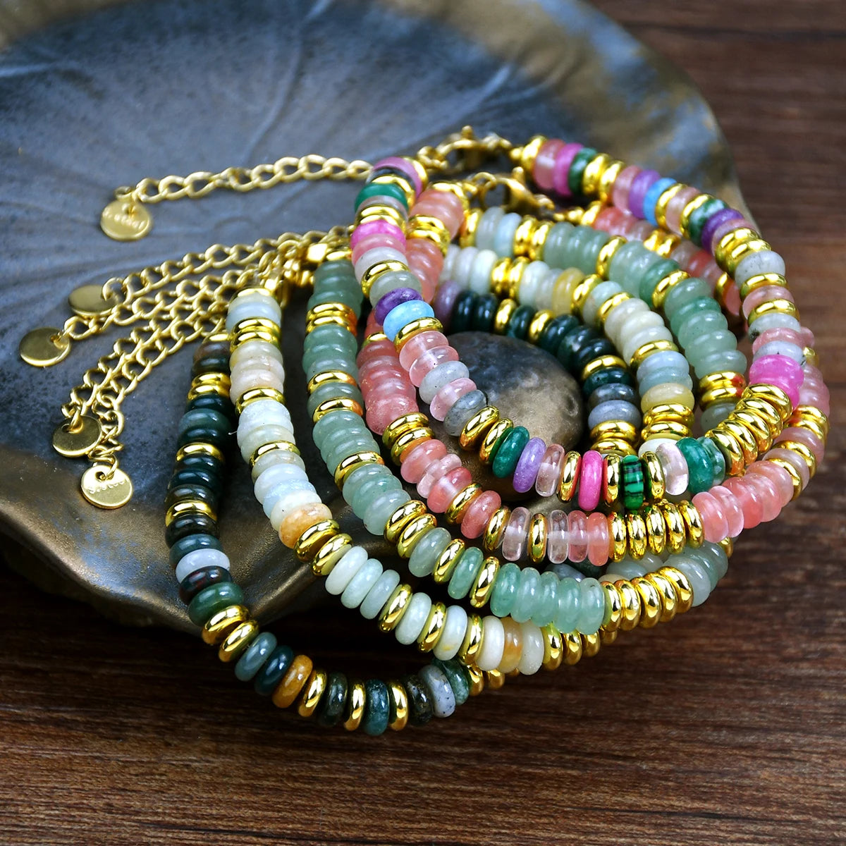 Colorful beaded bracelets with gold accents on a dark surface