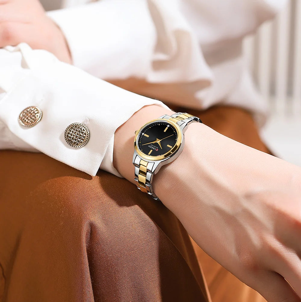 Gold and black watch on a wrist with a blurred background