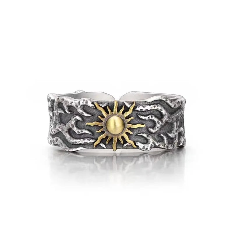 Silver ring with a textured design and gold sun emblem on a white background