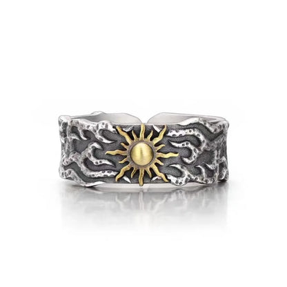 Silver ring with a textured design and gold sun emblem on a white background