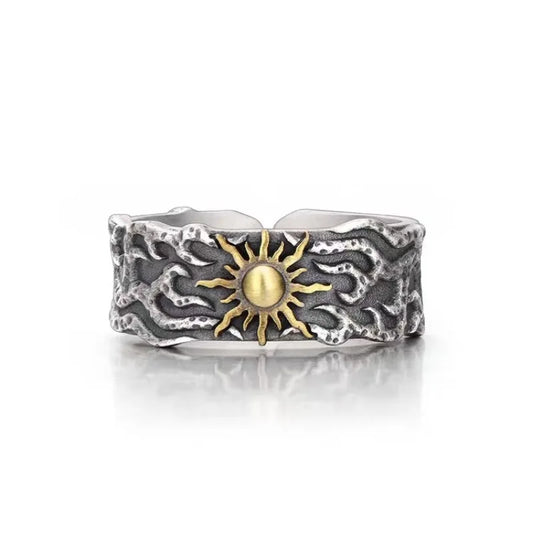 Silver ring with a textured design and gold sun emblem on a white background