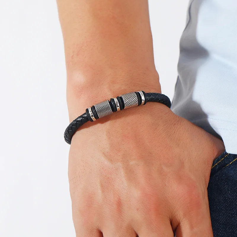 Black braided bracelet with silver accents on a wrist against a white background