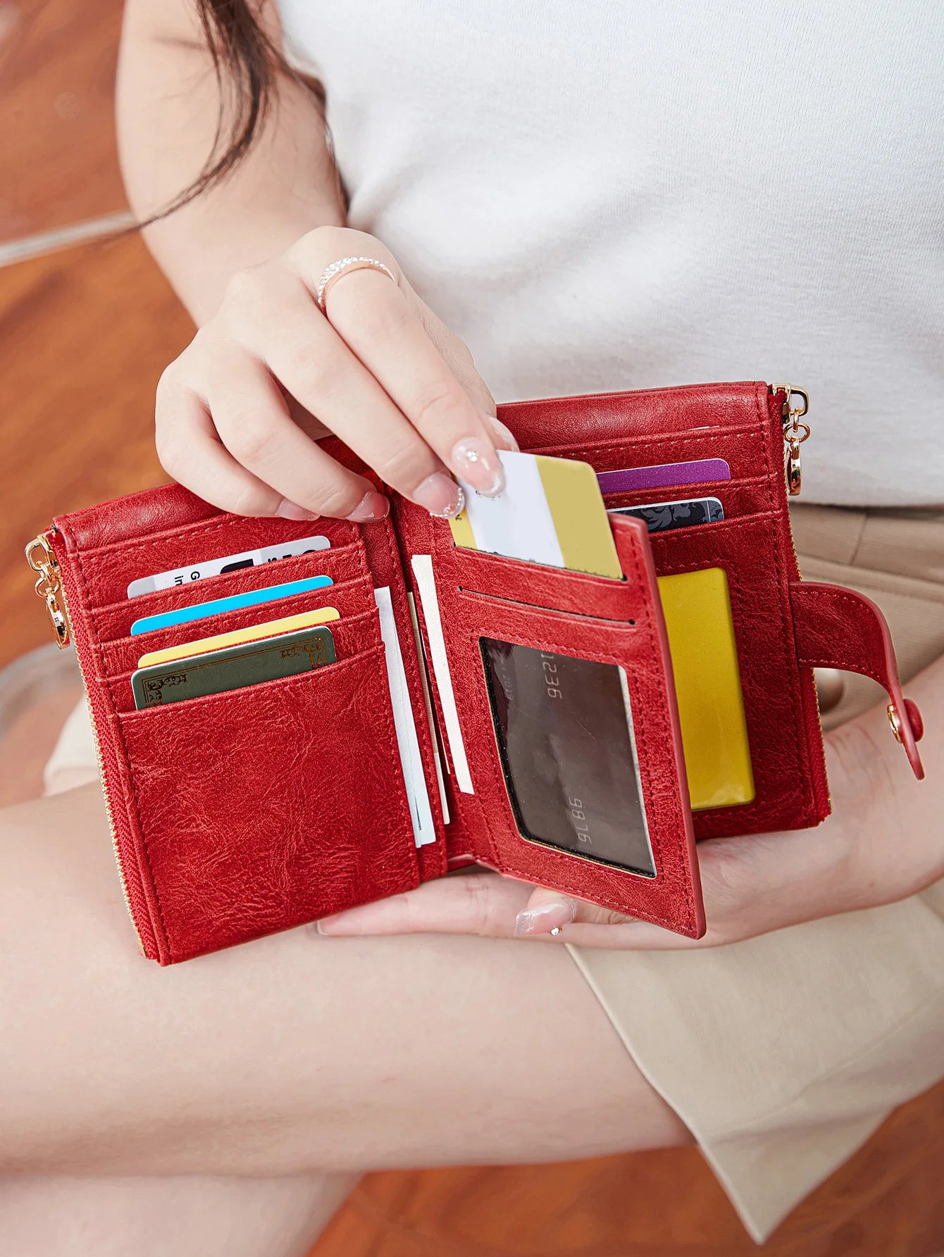 Red wallet with multiple card slots held by a person.