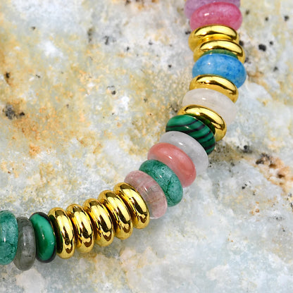 Multicolored beaded bracelet with gold accents on a textured stone surface