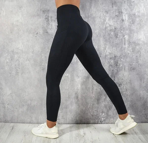 Person wearing black leggings against a gray concrete wall.