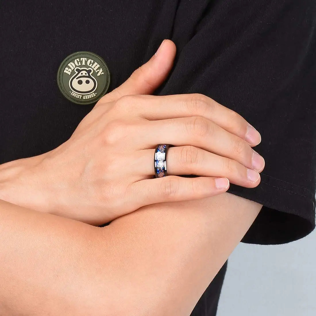 Person wearing a ring with a visible brand logo on a black shirt