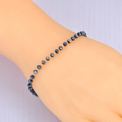 Black beaded bracelet on a wrist with a plain background