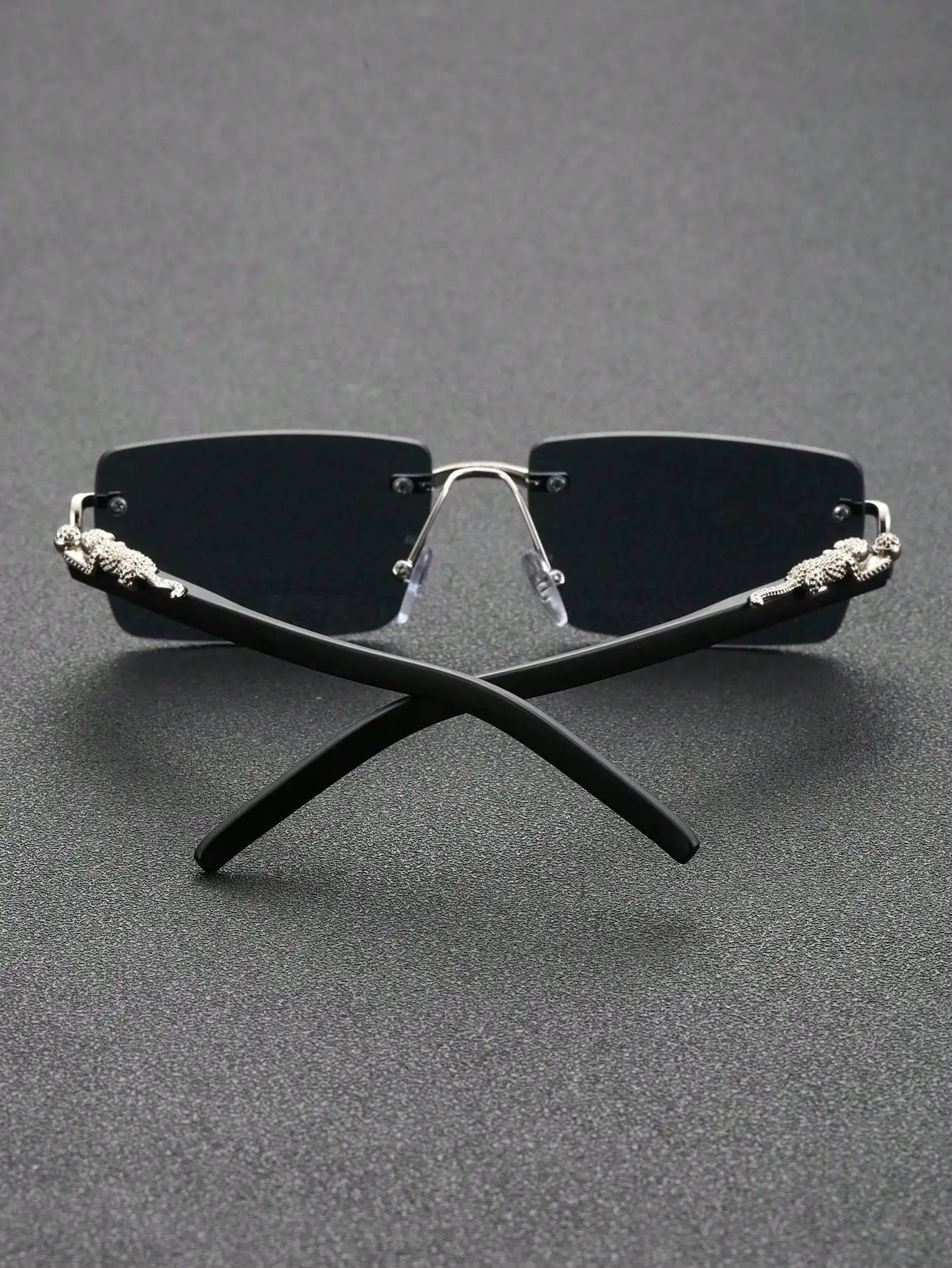 Black sunglasses with decorative metal accents on a gray background
