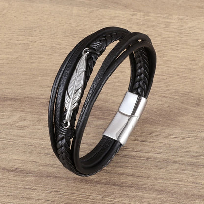 Black leather bracelet with silver feather charm on a wooden surface