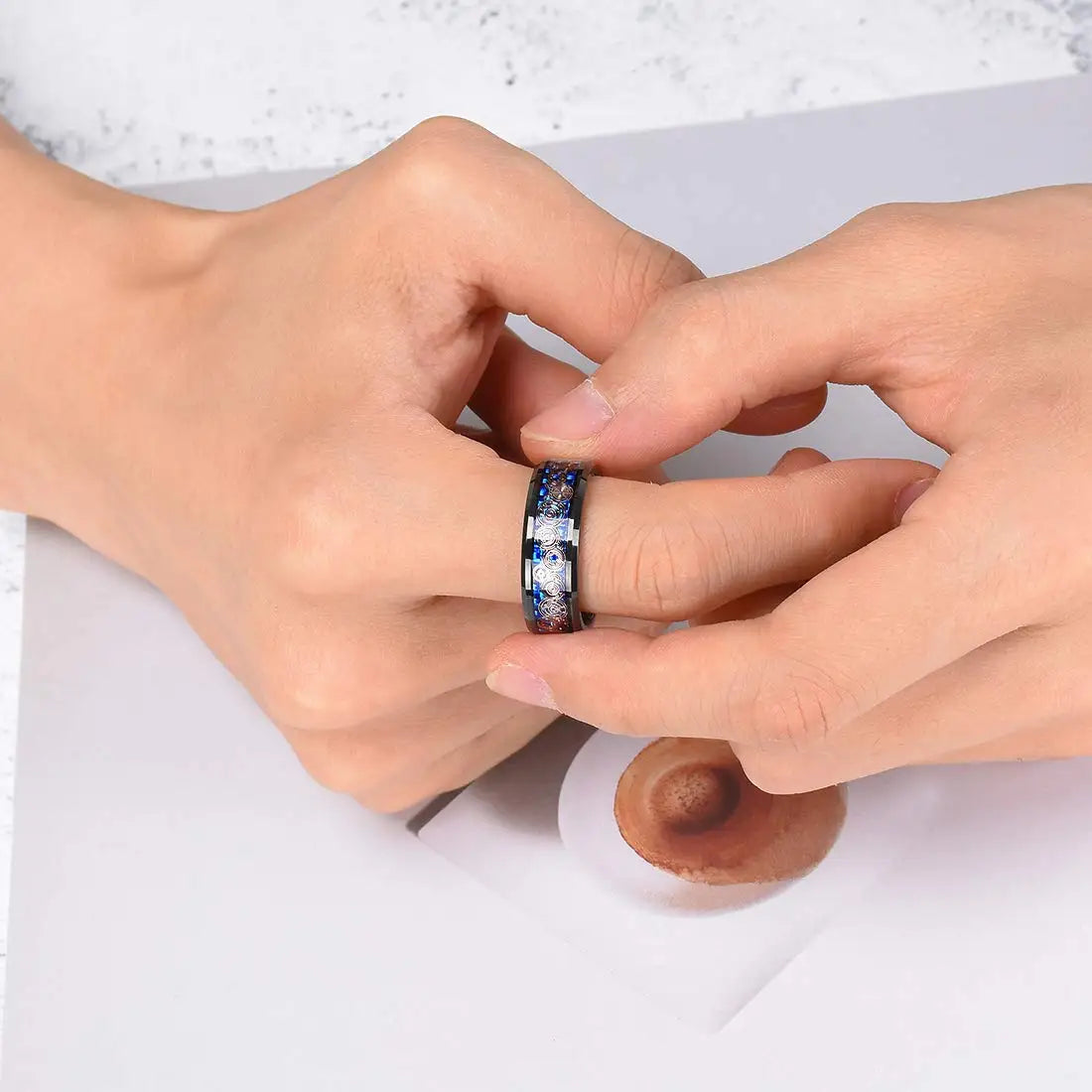 Close-up of two hands with a ring featuring blue stones on a white background