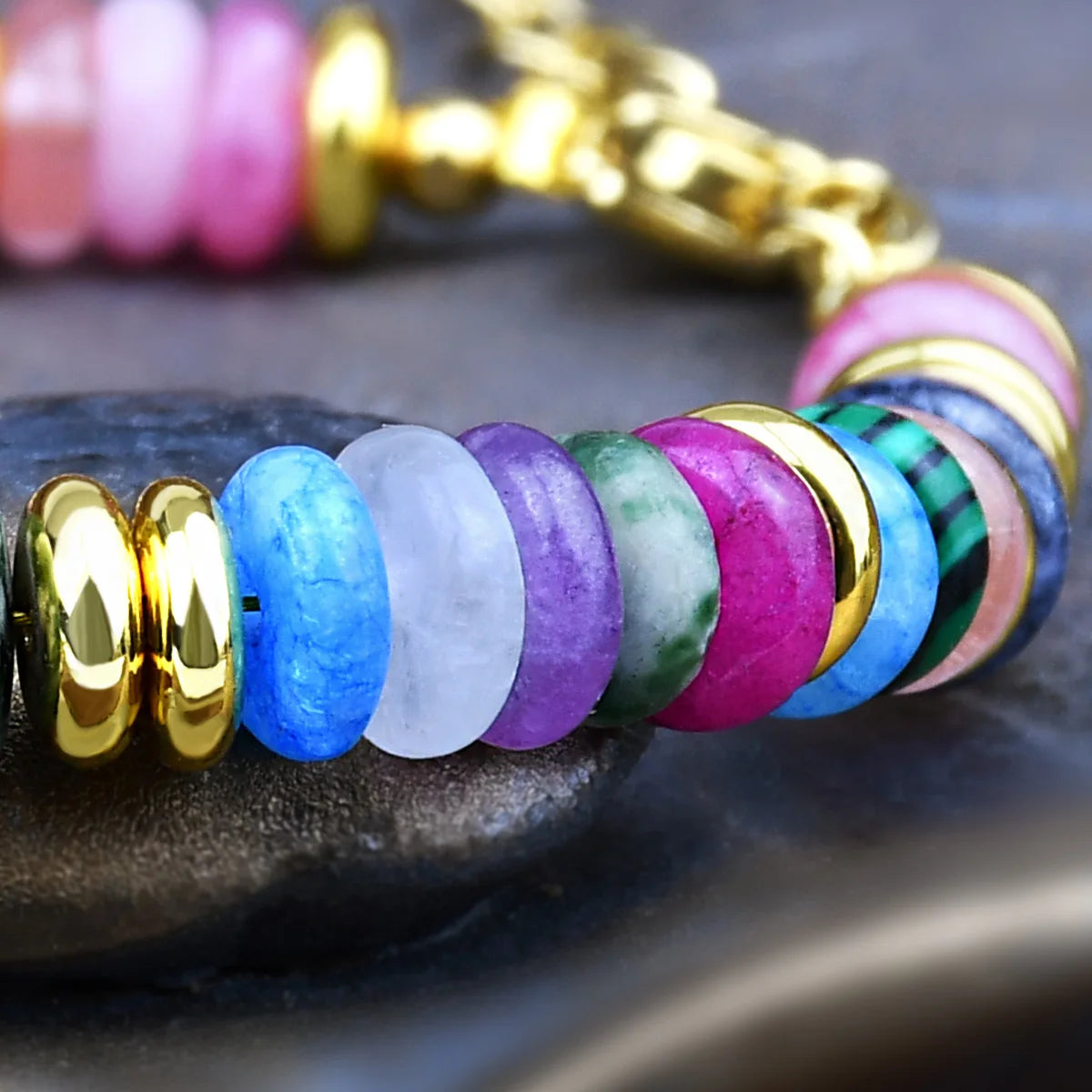 Colorful beaded bracelet with gold accents on a dark surface
