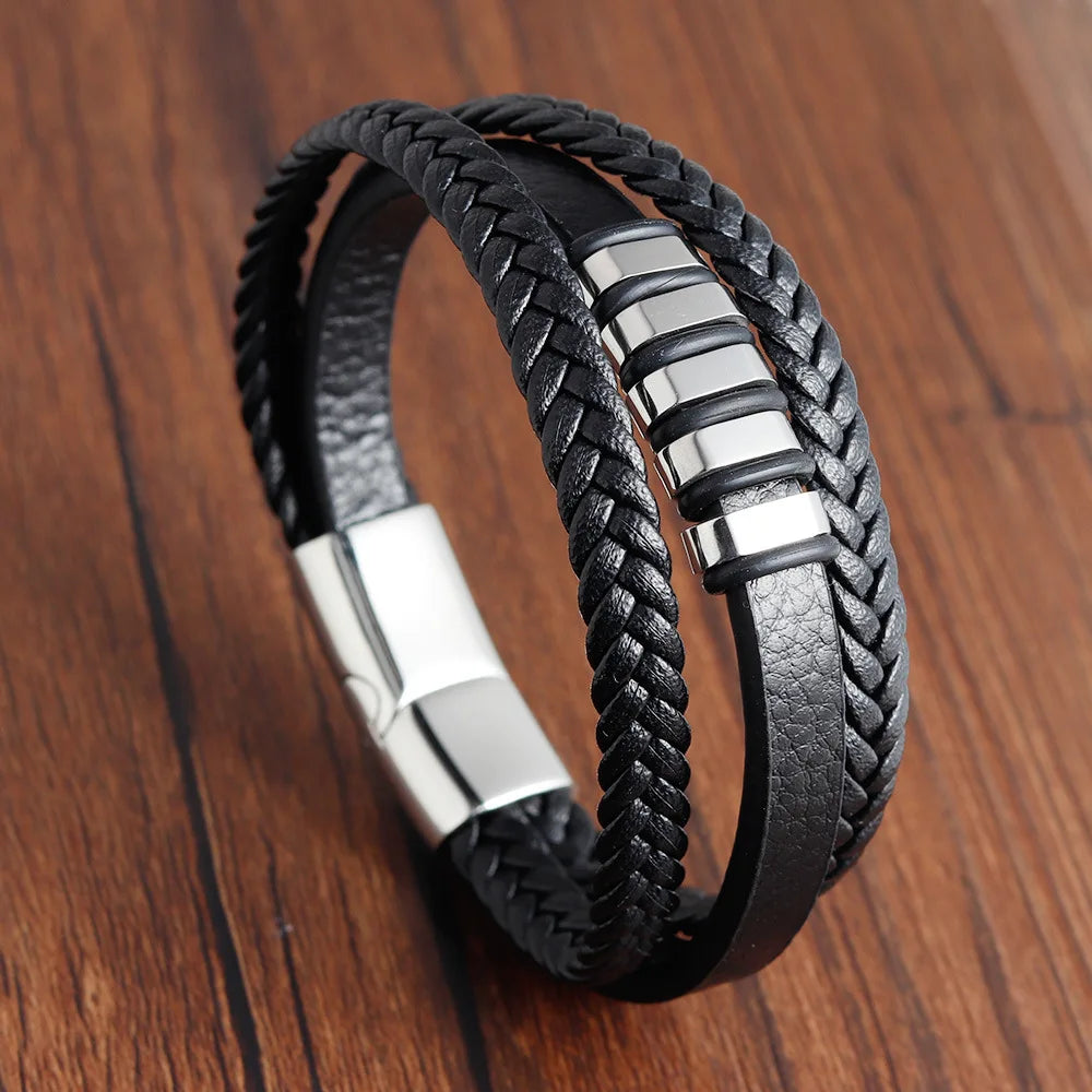 Black braided leather bracelet with silver accents on a wooden surface