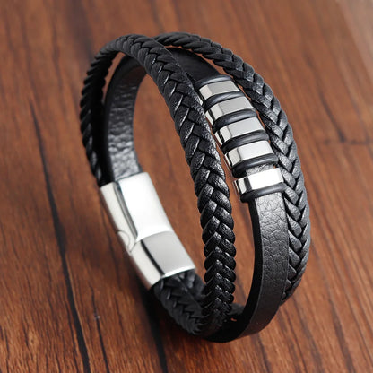 Black braided leather bracelet with silver accents on a wooden surface