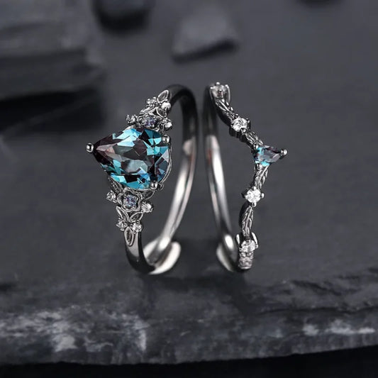 Silver ring with blue gemstone and matching earrings on a dark stone background