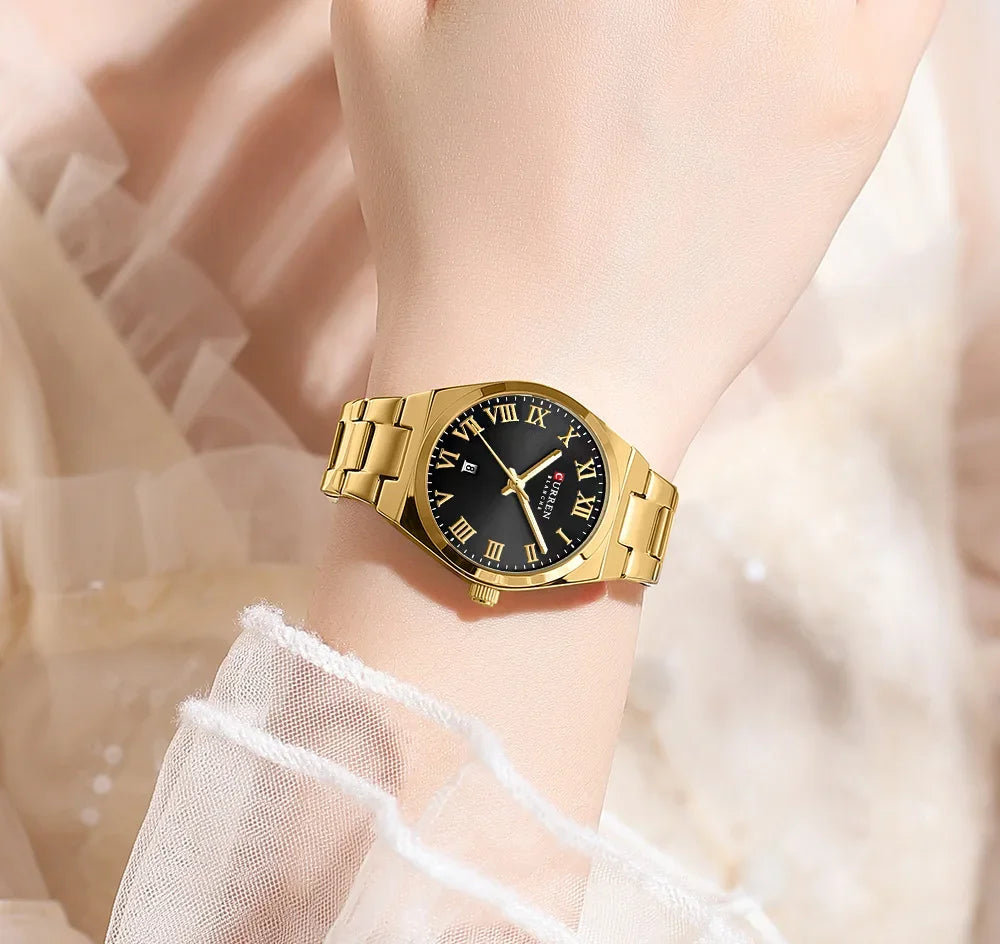 Gold wristwatch with black dial on a blurred background