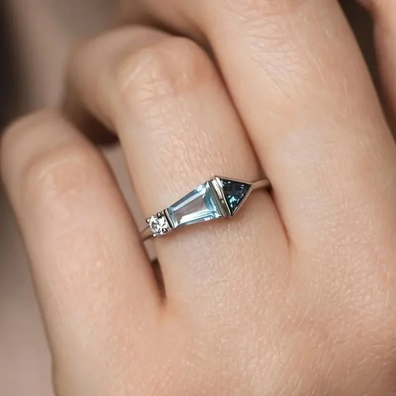 Close-up of a hand wearing a silver ring with a blue gemstone.