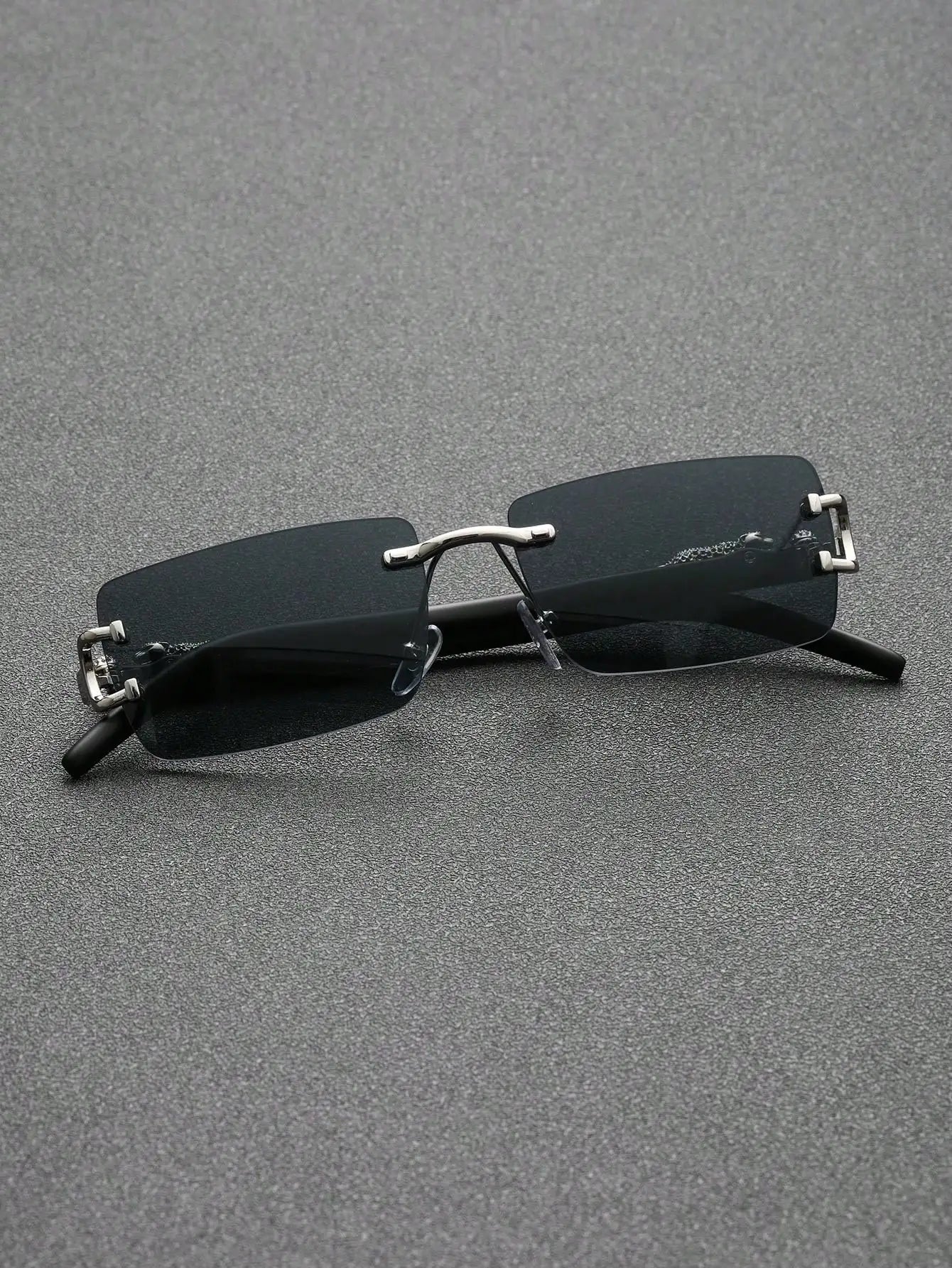 Sunglasses with thin frames and dark lenses on a gray surface