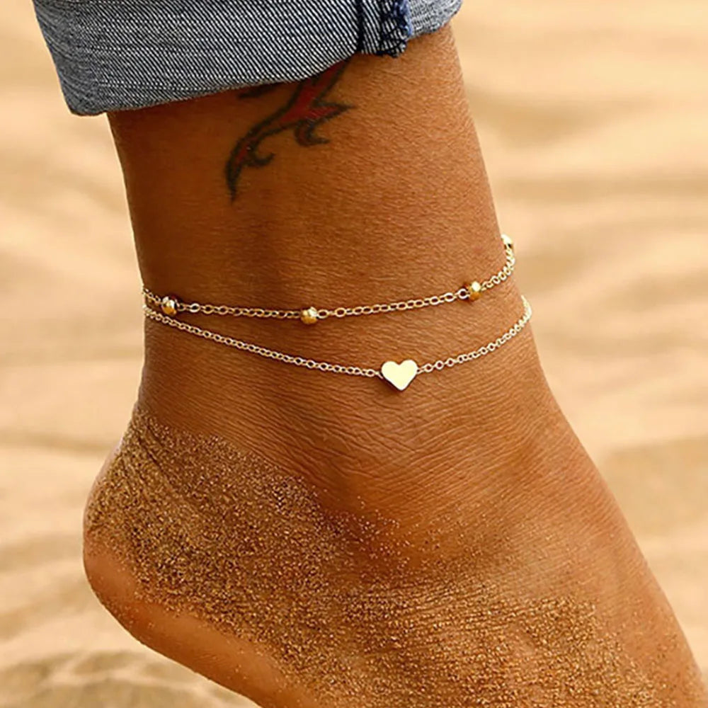 Ankle with gold anklets on a sandy background