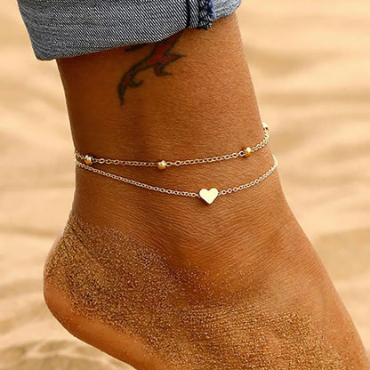 Ankle with gold anklets on a sandy background