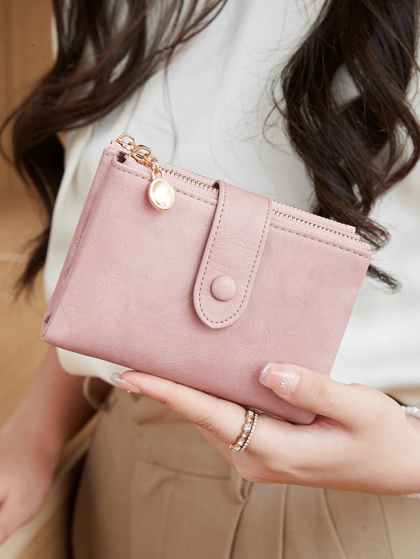 Pink wallet held by a person with a blurred background