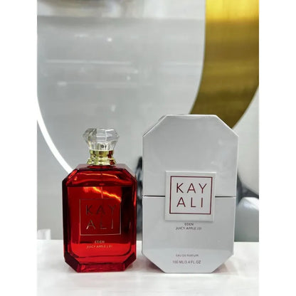 Red perfume bottle and white packaging with 'KAY ALI' branding on a reflective surface.