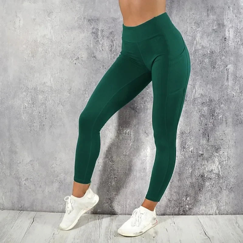 Person wearing green leggings and white sneakers against a gray concrete wall.