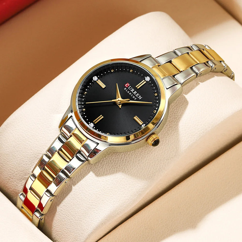 Two-tone gold and silver watch with black dial on a beige cushion