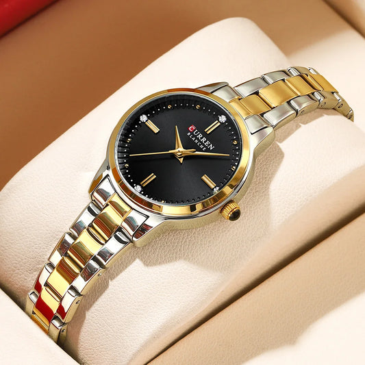 Two-tone gold and silver watch with black dial on a beige cushion
