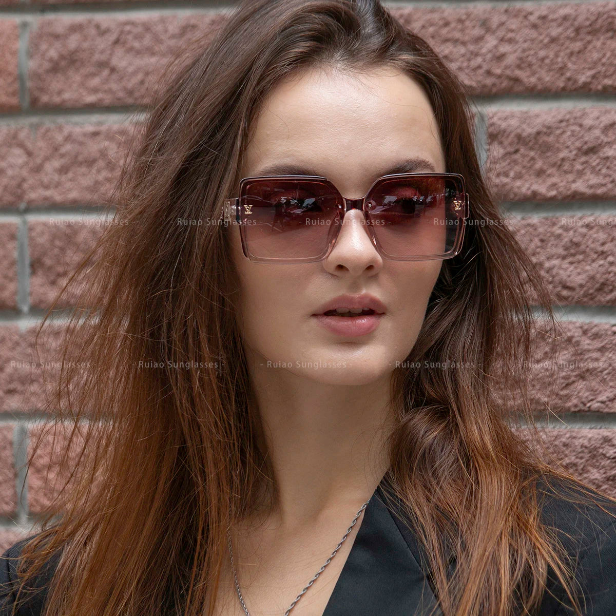 Woman wearing sunglasses with a brick wall background