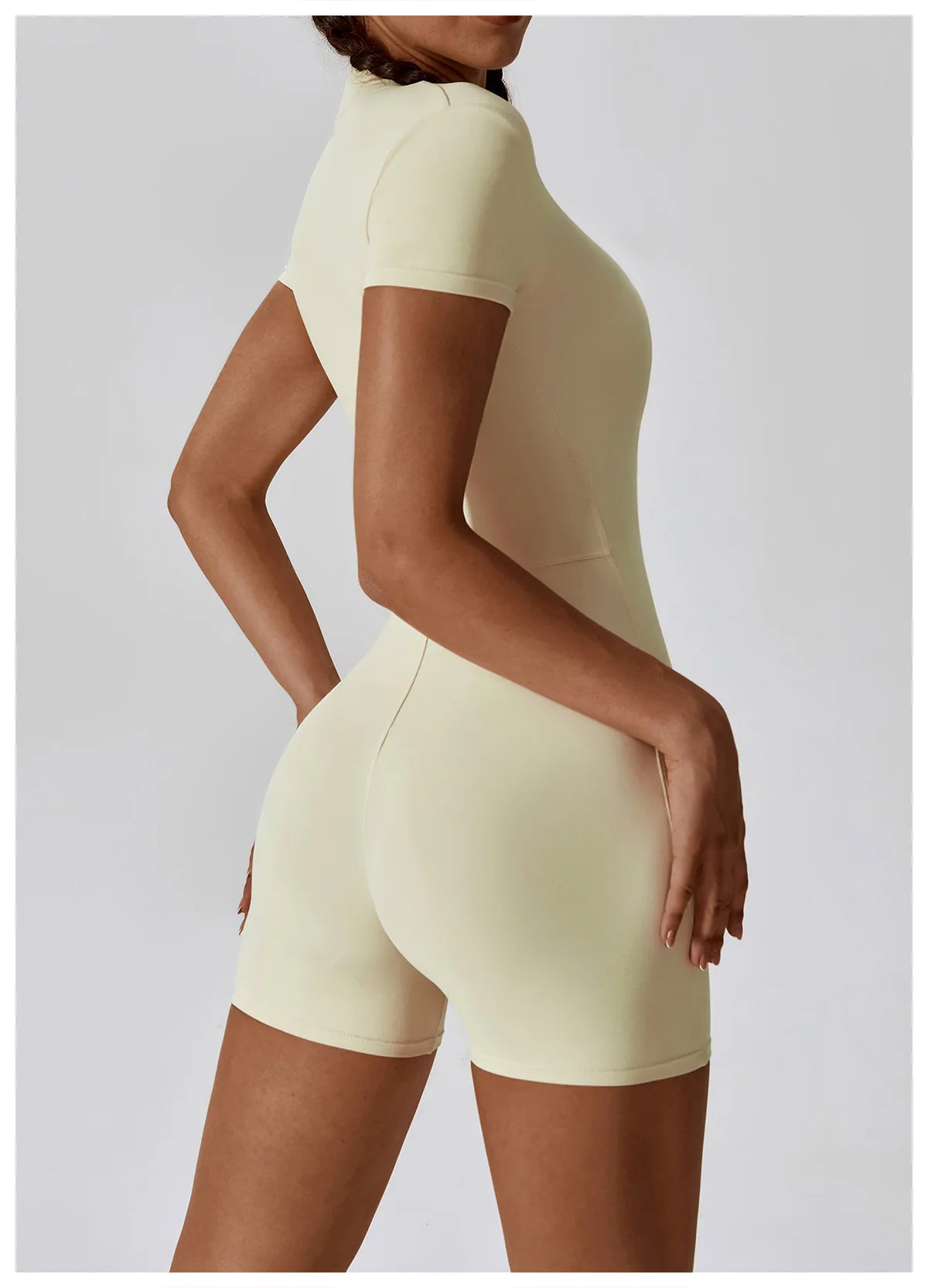 Person wearing a beige bodysuit against a light gray background