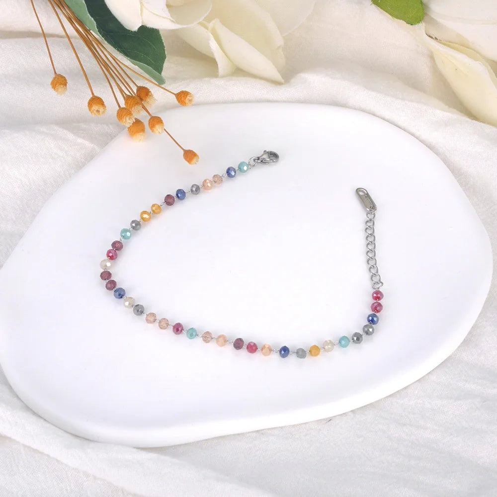 Multicolored beaded necklace on a white plate with flowers in the background
