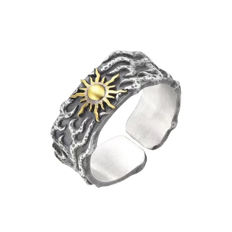 Silver ring with a gold sun design on a white background