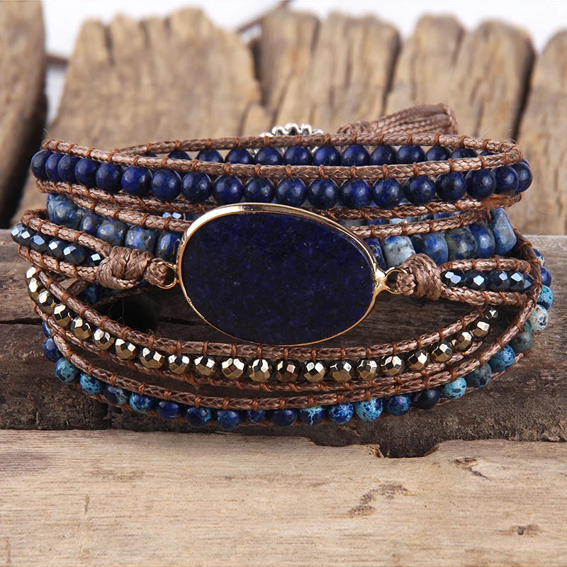 Multistrand bracelet with blue beads and a large central stone on a wooden surface