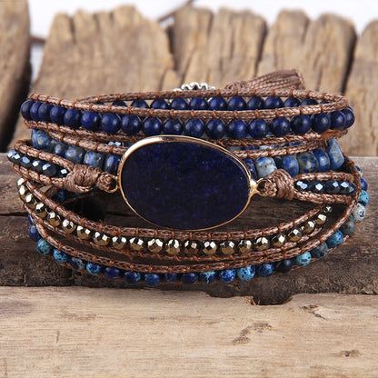 Multistrand bracelet with blue beads and a large central stone on a wooden surface