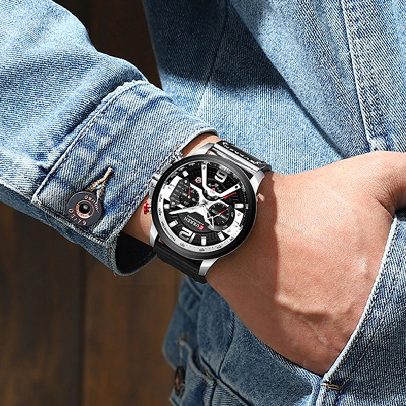 Person wearing a black wristwatch with a detailed face, set against a denim background.