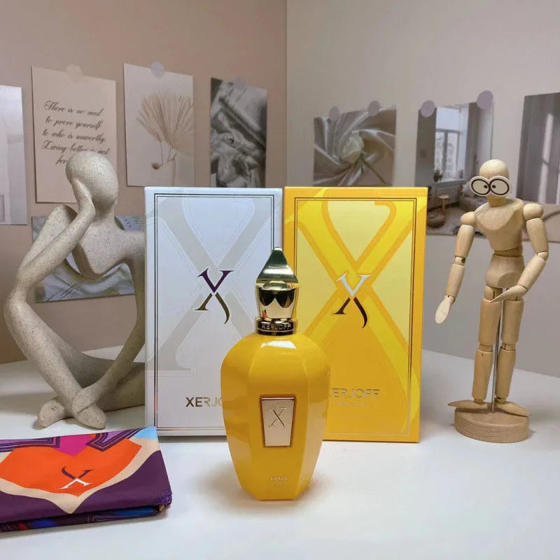 Yellow Xerjoff perfume bottle and packaging on a white surface with decorative elements.