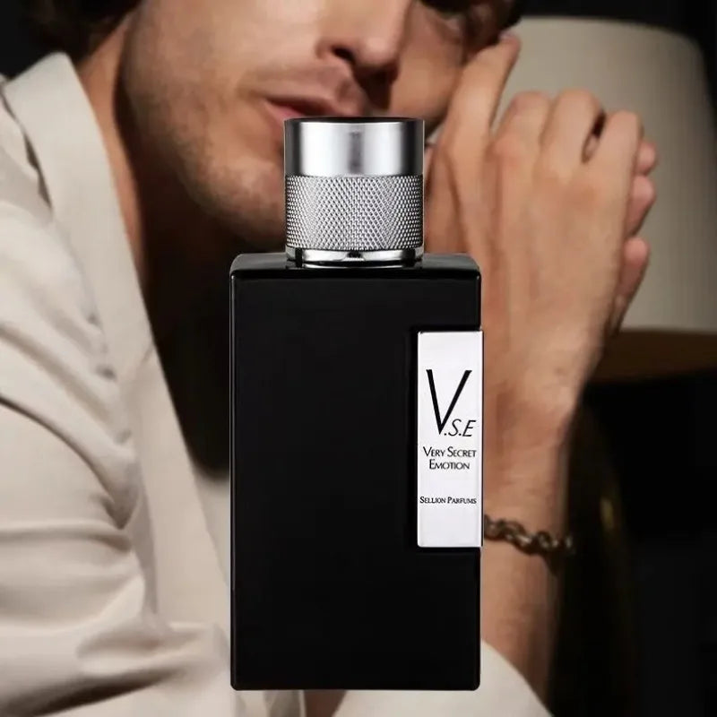 Black perfume bottle with silver cap held by a person, featuring 'V.S.E' branding.