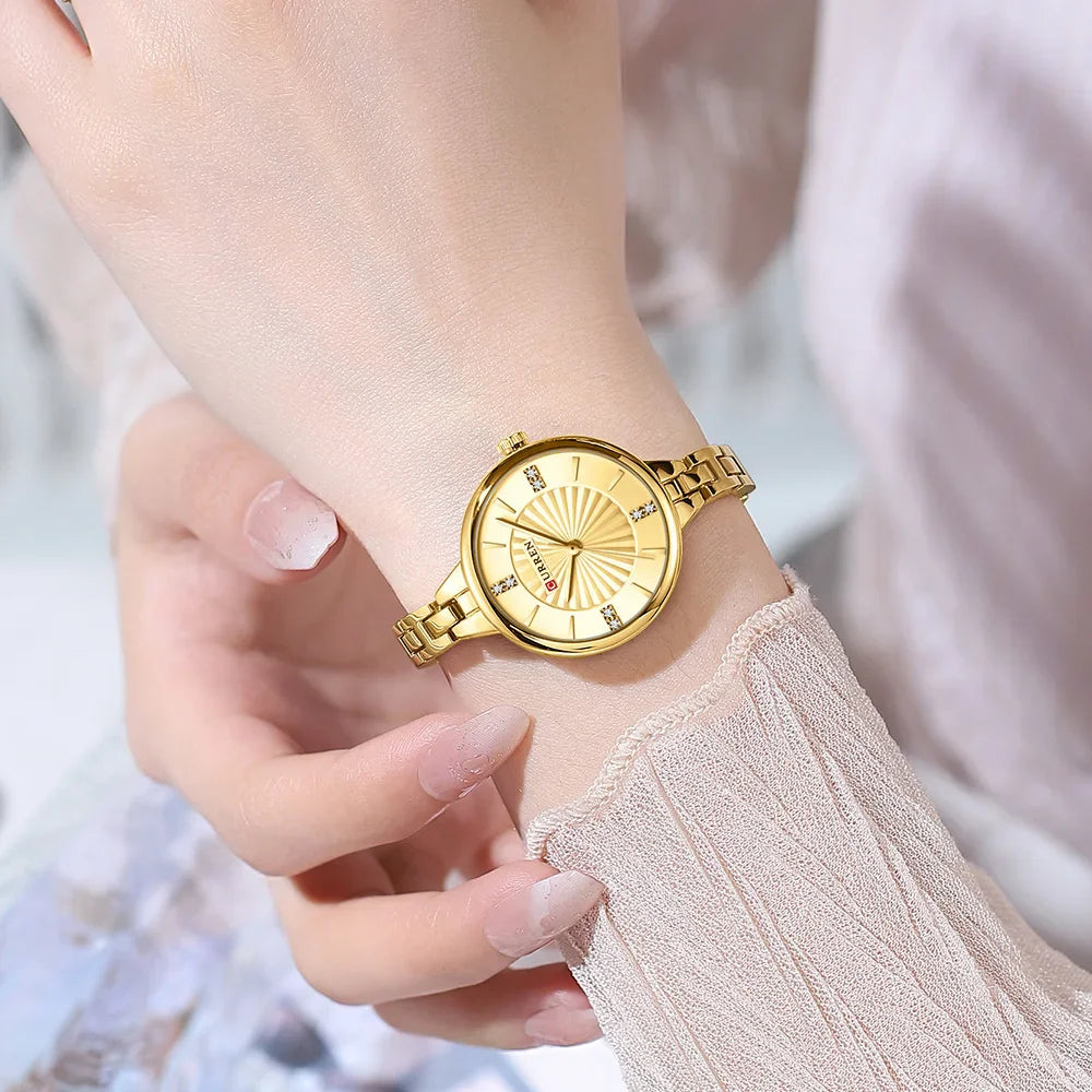 Gold wristwatch on a person's wrist with a blurred background